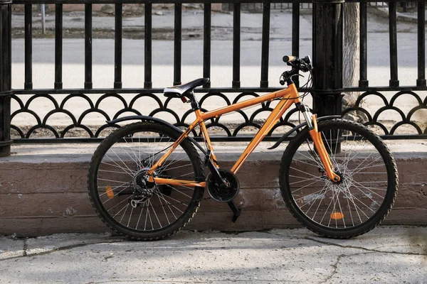 Bicicleta de montanha de estilo moderno trancada pela cerca na rua da cidade na cidade — Fotografia de Stock