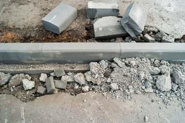 Kaldırımda Curdstones bir sınır yüklemek için çukur yakınındaki. Tarafta kırık asfalt yüzeye. Yol yüzeyi delikte. Yol çalışması tamiri