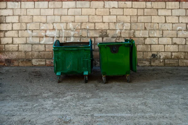 Beyaz tuğla önünde iki yeşil çöp Dumpsters metin için yer ile Önden Görünüm duvar. İki metal çöp kutular gettosundaki meydanın kenarında. — Stok fotoğraf