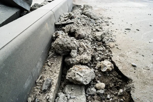 Montones de asfalto demolido tumbado en la acera cerca de la fosa para instalar un bordillo. Asfalto roto. Un agujero en la superficie de la carretera. Reparación de obras viarias —  Fotos de Stock
