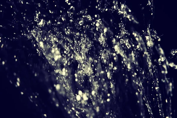 Krople wody latać w powietrzu na ciemnym tle — Zdjęcie stockowe