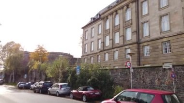 Bonn Almanya, 06 Kasım 2019: Ren seti 4K 50fps kaldırımında birçok araba park halindeyken küçük kırmızı bir araba sokakta sürüyordu.