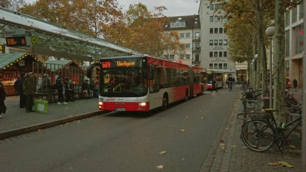 Bonn Německo, 23. prosince 2019: Na autobusové zastávce stojí dva autobusy, kolem projíždějí cyklisté a chodci — Stock video