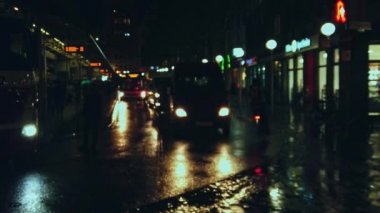 Otobüs durağı gece duşlarla doldu, bir sürü araba, yayalar, bisikletçiler hareket ediyor.