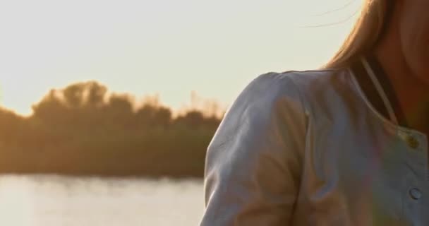 Amatör video av den vackra ansiktet av en flicka med långt blont hår mot solnedgången. — Stockvideo