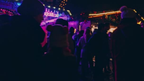 Bonn Németország, 2019. dec. 23.: Emberek tömegei sétálnak a karácsonyi vásáron, neon fény világítja meg a köröket — Stock videók
