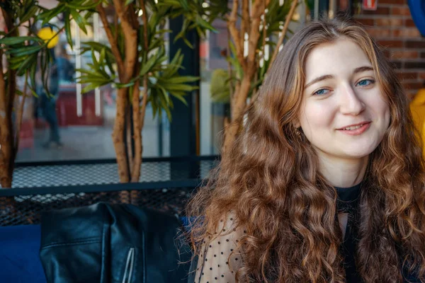 Menina encaracolado com poses de cabelo vermelho no café sorrindo para a câmera — Fotografia de Stock