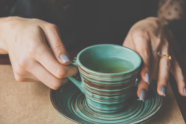 Vrouwen handen houden een groene keramische beker met een creatieve Japanse stijl patroon — Stockfoto