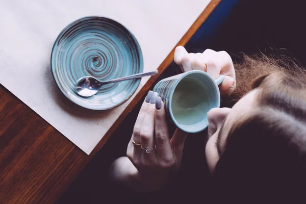 Een uitzicht van boven van een meisje drinkend thee van een klein kopje. — Stockfoto
