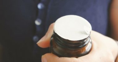 Son sınıf öğrencisi bir kadın reçeteli kapsül şişesini açmaya çalışıyor..