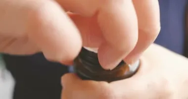 Kıdemli kadın mühürlü ilaç şişesini açmaya çalışıyor.