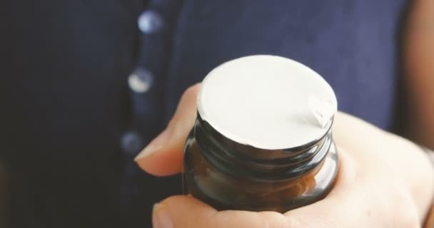 Une femme âgée peine à ouvrir son flacon de capsules de prescription .