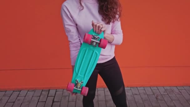 The girl throws her skateboard up and smiles joyfully, then drops it down and looks at the camera. — Stock Video