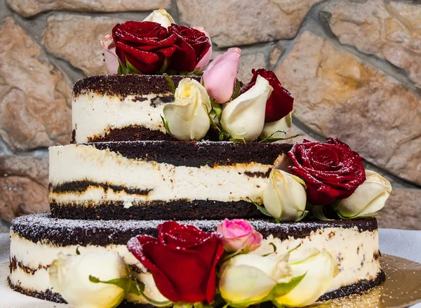 cake with natural flowers against the backdrop of a stone wall