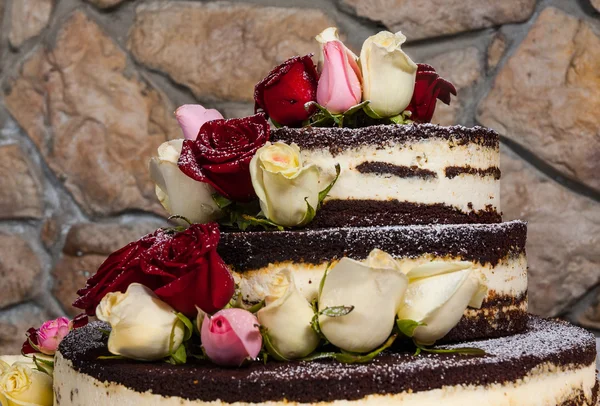 cake with natural flowers against the backdrop of a stone wall