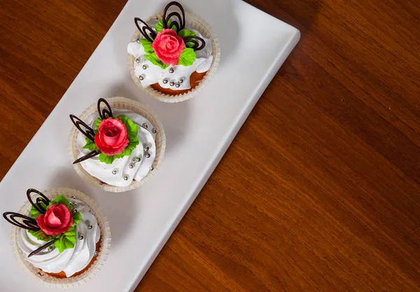 Deliciosos cupcakes de terciopelo rojo decorados con rosa sobre fondo de madera —  Fotos de Stock