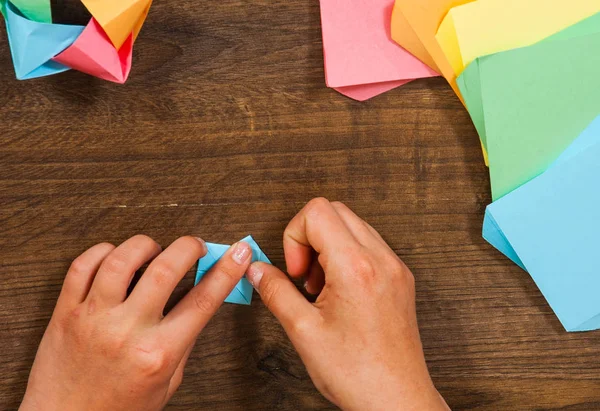 Das Kind legt die Module. Kinderkreationen aus Papier, Origami-Basteln, Basteln für Kinder. Handgemacht. auf hölzerner Tischplatte. — Stockfoto