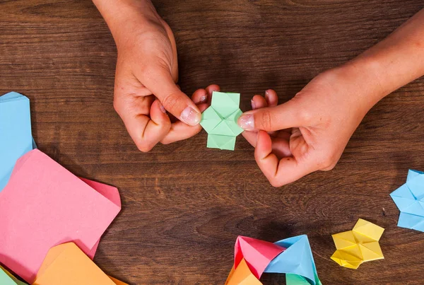 Il bambino mette i moduli. creatività dei bambini fatta di carta, artigianato origami, artigianato per bambini. Fatto a mano. su tavolo in legno vista dall'alto . — Foto Stock