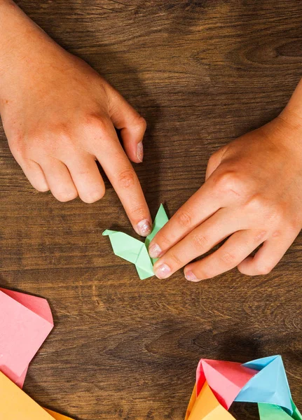 Het kind zet de modules. Kinder creativiteit gemaakt van papier, origami, ambachten, handwerk voor kinderen. Handgemaakte. op houten tafel bovenaanzicht. — Stockfoto