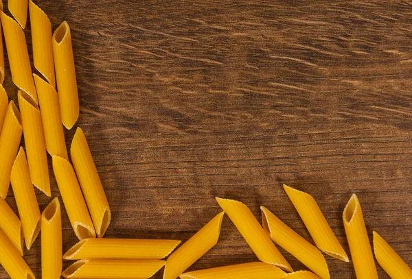 Italienische rohe Rigatoni Pasta Penne auf Holztisch mit Kopierraum. Ansicht von oben — Stockfoto