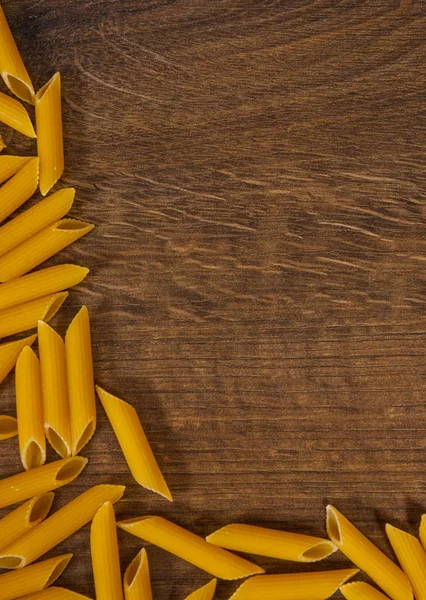 Pena italiana de pasta rigatoni cruda sobre mesa de madera con espacio para copiar. vista superior — Foto de Stock