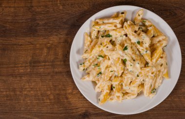 Kopya alanı ile tahta masada Krema soslu Penne makarna. Üstten Görünüm
