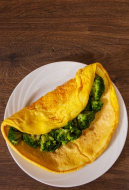 Brokoli kopya alanı ile ahşap masa üzerinde beyaz bir tabakta omlet. Üstten Görünüm