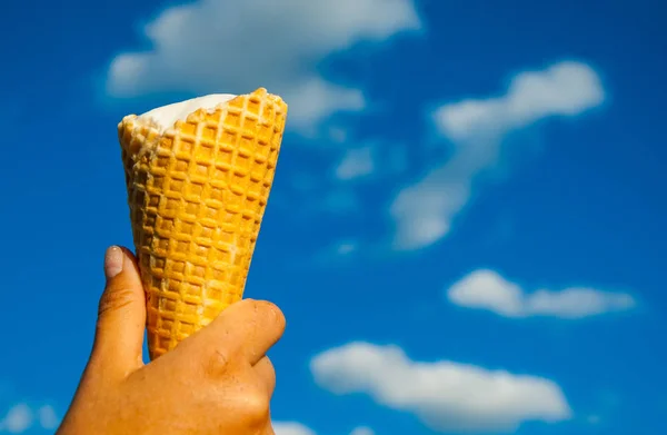Конус мороженого от мягкого сливочного молока в жаркий летний день на голубом фоне неба с копировальным пространством . — стоковое фото
