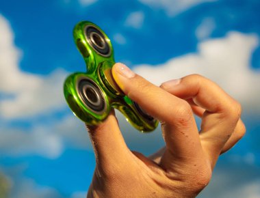 Popüler yeşil topluca spinner oyuncak gökyüzü arka plan üzerinde tutan el