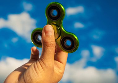 Popüler yeşil topluca spinner oyuncak gökyüzü arka plan üzerinde tutan el