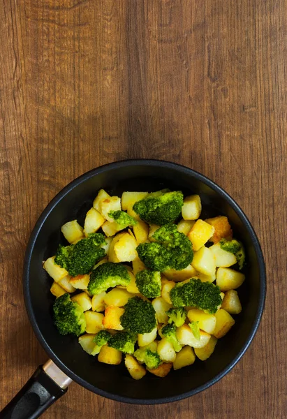 Brócoli con patatas en una sartén sobre el fondo de la mesa de madera marrón. con espacio para copias. vista superior . — Foto de Stock