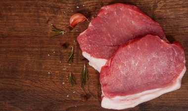 çiğ domuz eti biftek ve sarımsak, biber kahverengi ahşap masa arka plan üzerinde. rustik mutfak masasında kopya alanı ile. Üstten Görünüm.