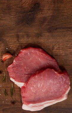 çiğ domuz eti biftek ve sarımsak, biber kahverengi ahşap masa arka plan üzerinde. rustik mutfak masasında kopya alanı ile. Üstten Görünüm.