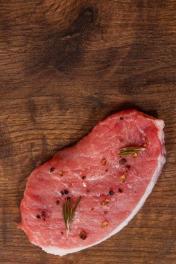 çiğ domuz eti chop biftek kahverengi ahşap masa arka plan üzerinde. rustik mutfak masasında kopya alanı ile. Üstten Görünüm.