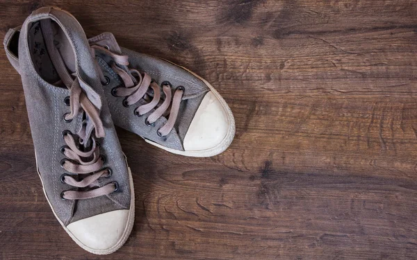 Par de viejas zapatillas sucias sobre el fondo marrón de madera. con espacio para copias. vista superior . — Foto de Stock