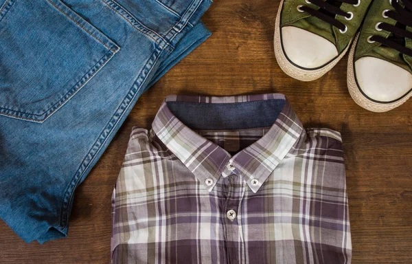 Set van cool mode mannen casual outfit op houten tafel, blauwe jeans broek, sneaker, bovenaanzicht. — Stockfoto