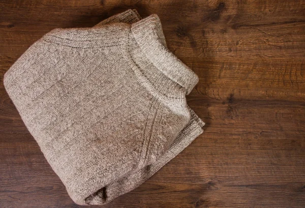 グレーのウールのセーターは、茶色の木製の背景上に畳んだ。コピー スペース。トップ ビュー. — ストック写真