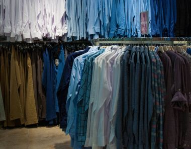 Men's plaid shirts in different colors on hangers in a retail shop clipart