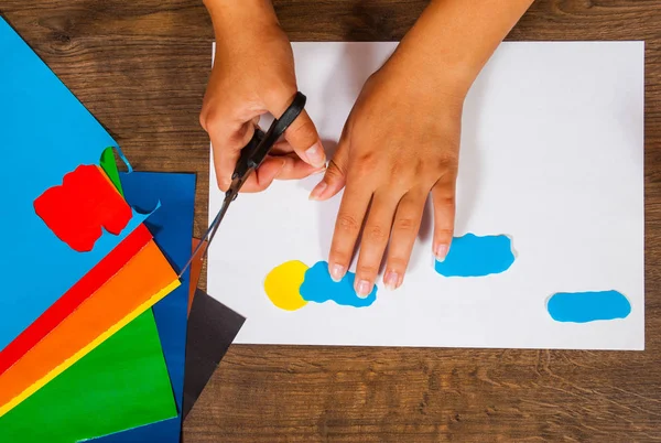 Il bambino taglia fuori la carta. Fogli di carta colorata. Arte per bambini. Concetto artigianale. Fatto a mano. su tavolo in legno vista dall'alto . — Foto Stock