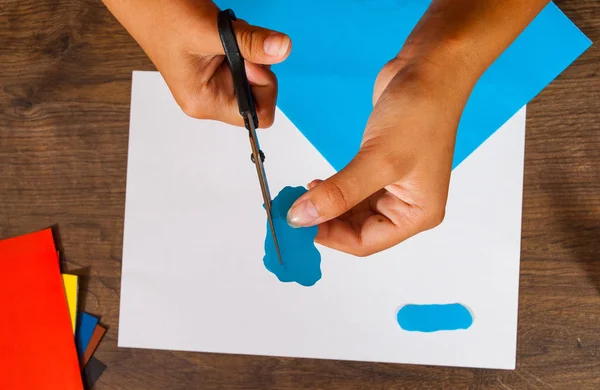 Il bambino taglia fuori la carta. Fogli di carta colorata. Arte per bambini. Concetto artigianale. Fatto a mano. su tavolo in legno vista dall'alto . — Foto Stock