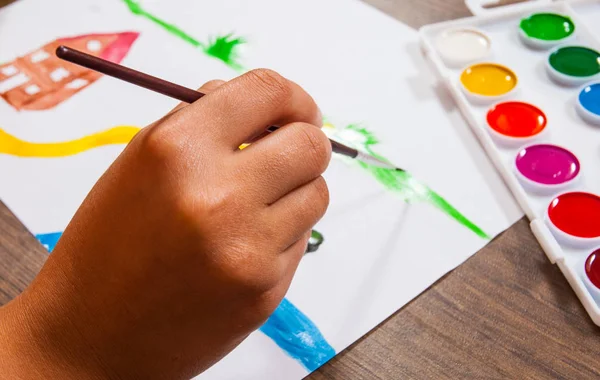 Die Hand des Kindes zeichnet ein Bild mit Aquarellen — Stockfoto