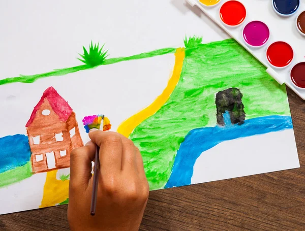 La main de l'enfant dessine une image avec des aquarelles. vue de dessus — Photo