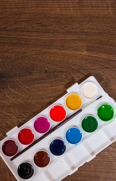 Colores acuáticos en estuche de plástico blanco sobre mesa de madera. con espacio para copias. vista superior . — Foto de Stock