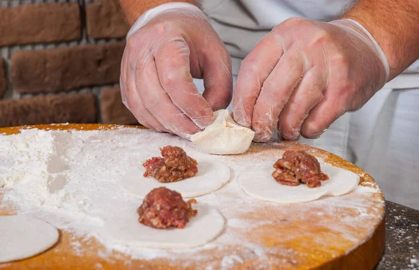 Mãos chef em processo de fazer bolinhos caseiros, ravioli ou pelmeni — Fotografia de Stock