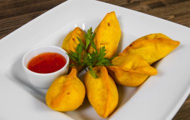 Ahşap arka plan üzerinde soslu kızarmış mantı.