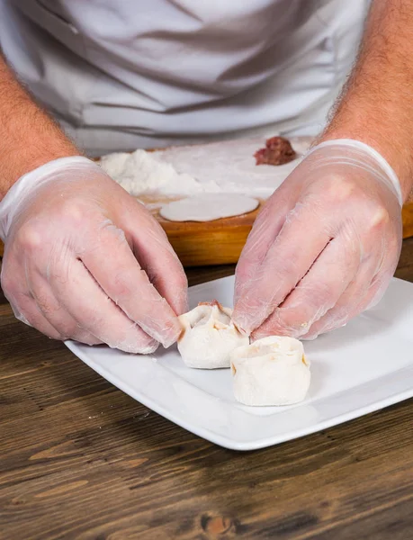 Manos del chef en proceso de fabricación de albóndigas caseras, ravioles o pelmeni —  Fotos de Stock
