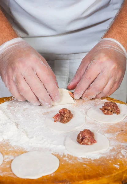 Mãos chef em processo de fazer bolinhos caseiros, ravioli ou pelmeni — Fotografia de Stock
