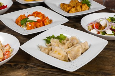 Farklı salata, köfte ve mantı ahşap bir masa üzerinde