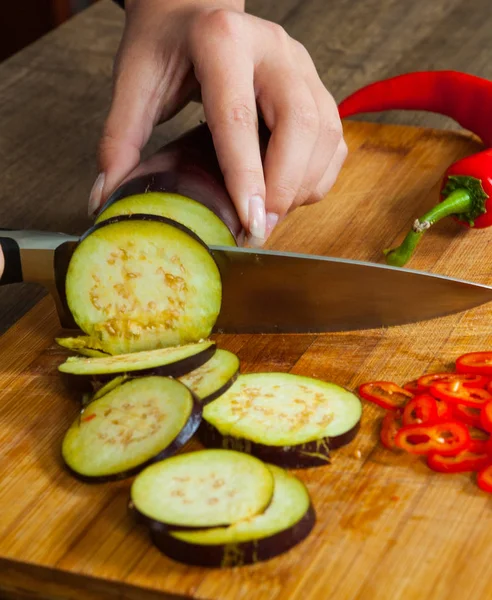 Chefs hands chopping eggplant on wooden board — Stock Photo, Image