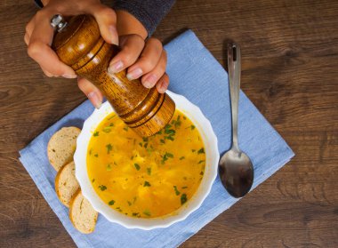 Eller kadın kara biber karabiber değirmeni kullanarak ekleme. ahşap bir arka plan üzerinde